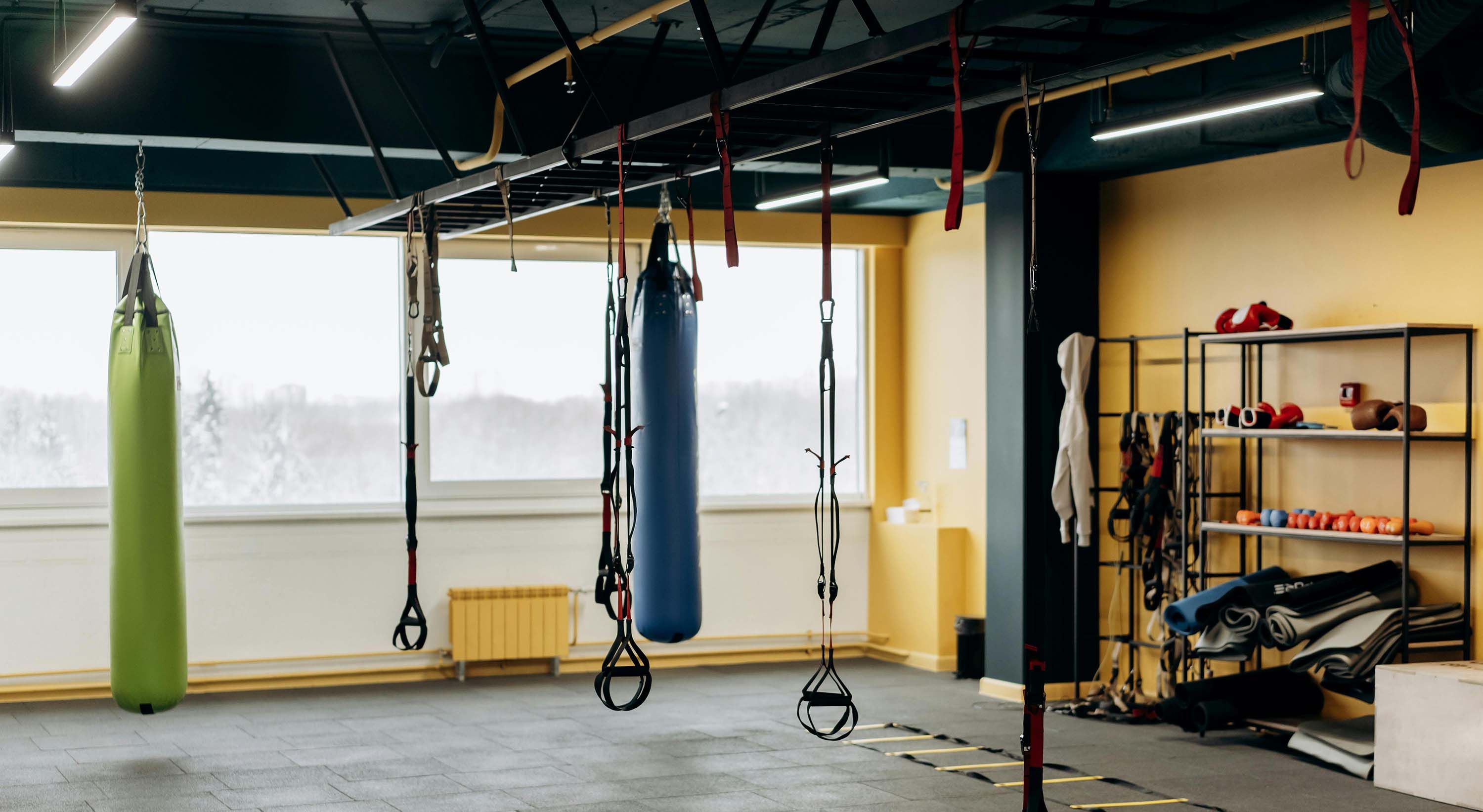 home gym with yellow walls and hanging bags